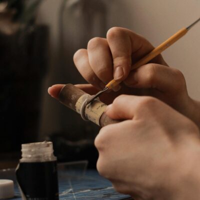 Close-up of hands meticulously crafting a ring with detailed tools at a workbench.