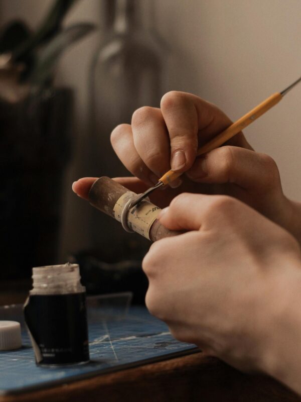 Close-up of hands meticulously crafting a ring with detailed tools at a workbench.