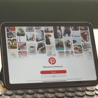 Tablet showing Pinterest homepage on a modern desk setup with a keyboard.